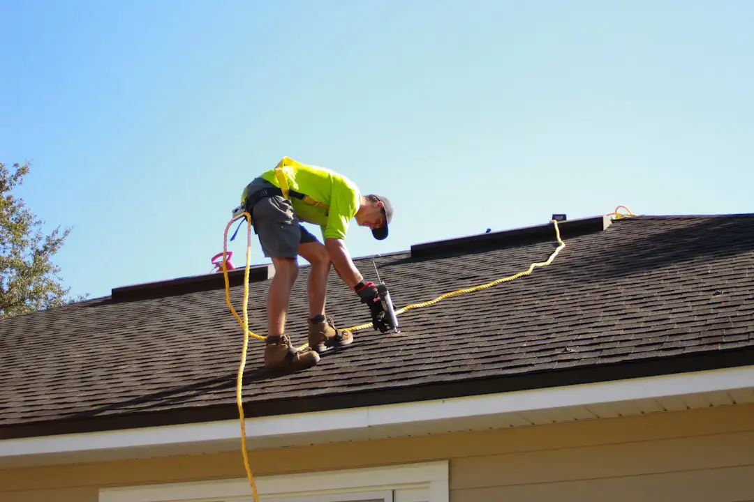 Roesler's roofing professional working on a shingle roof with a safety harness